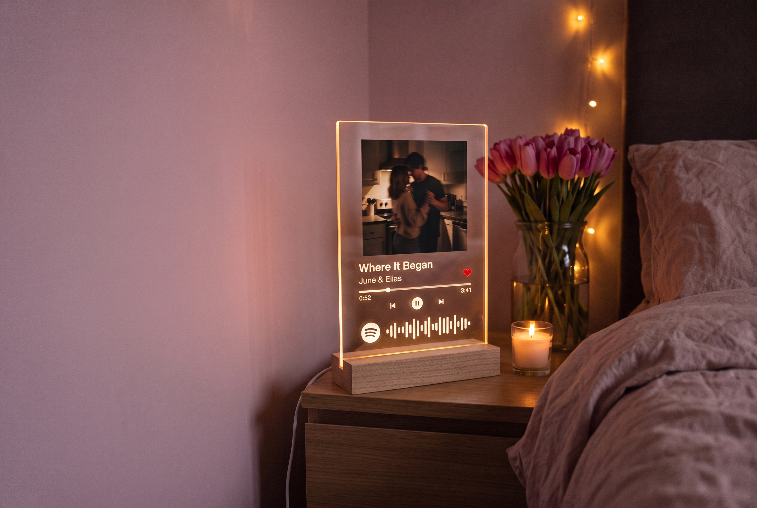 Personalisiertes Spotilight Acrylglas-Bild leuchtet abends auf einem Nachttisch neben Tulpen und einer Kerze