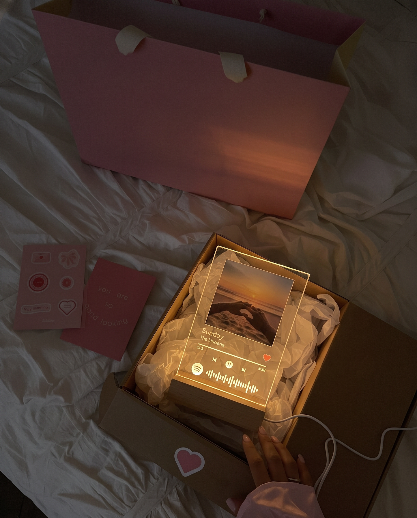 A Spotilight being lifted from its gift box at night, glowing among the tissue paper
